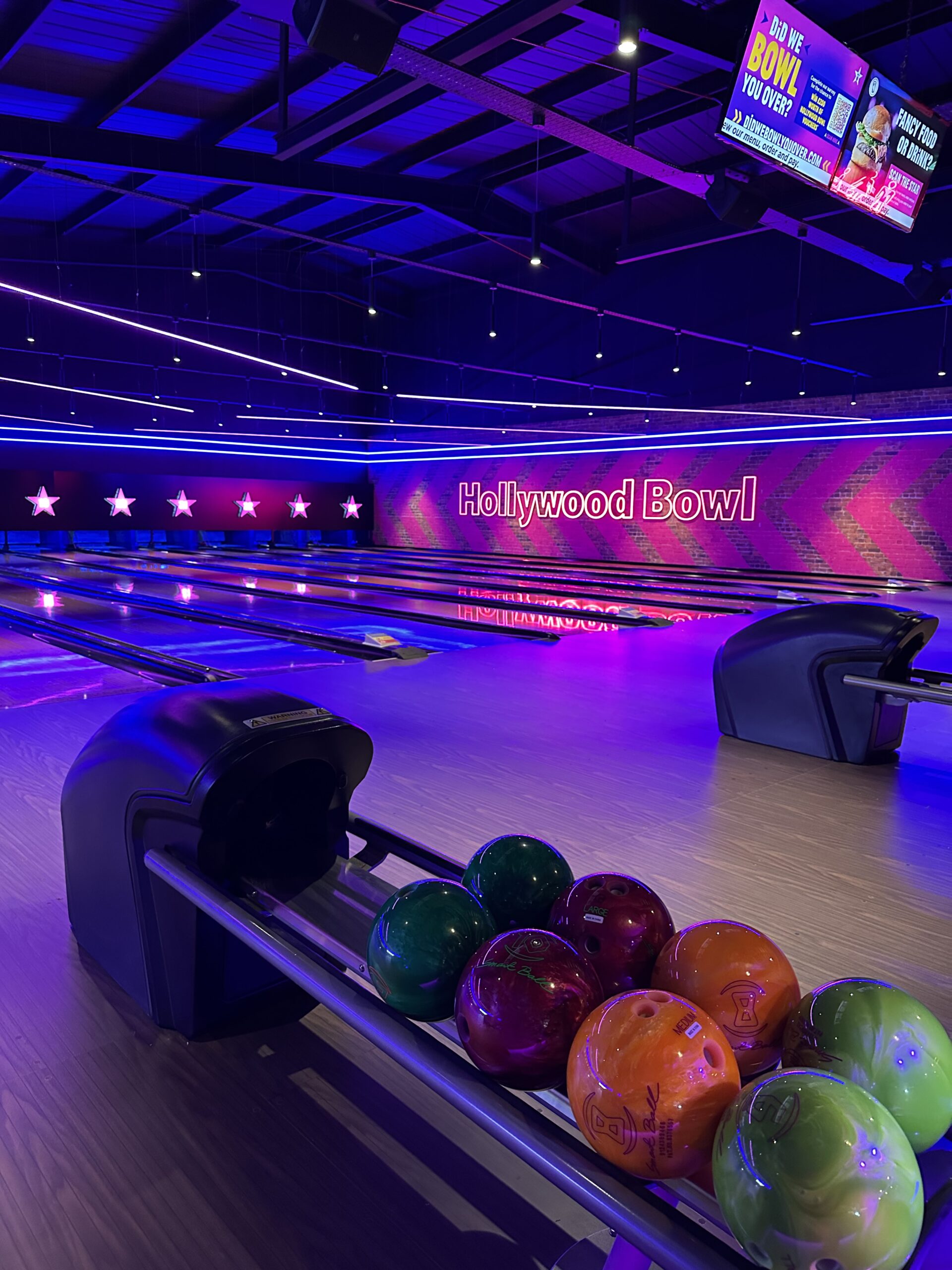 Colorful bowling balls in front of neon-lit lanes at the newly refurbished Hollywood Bowl Liverpool Edge Lane